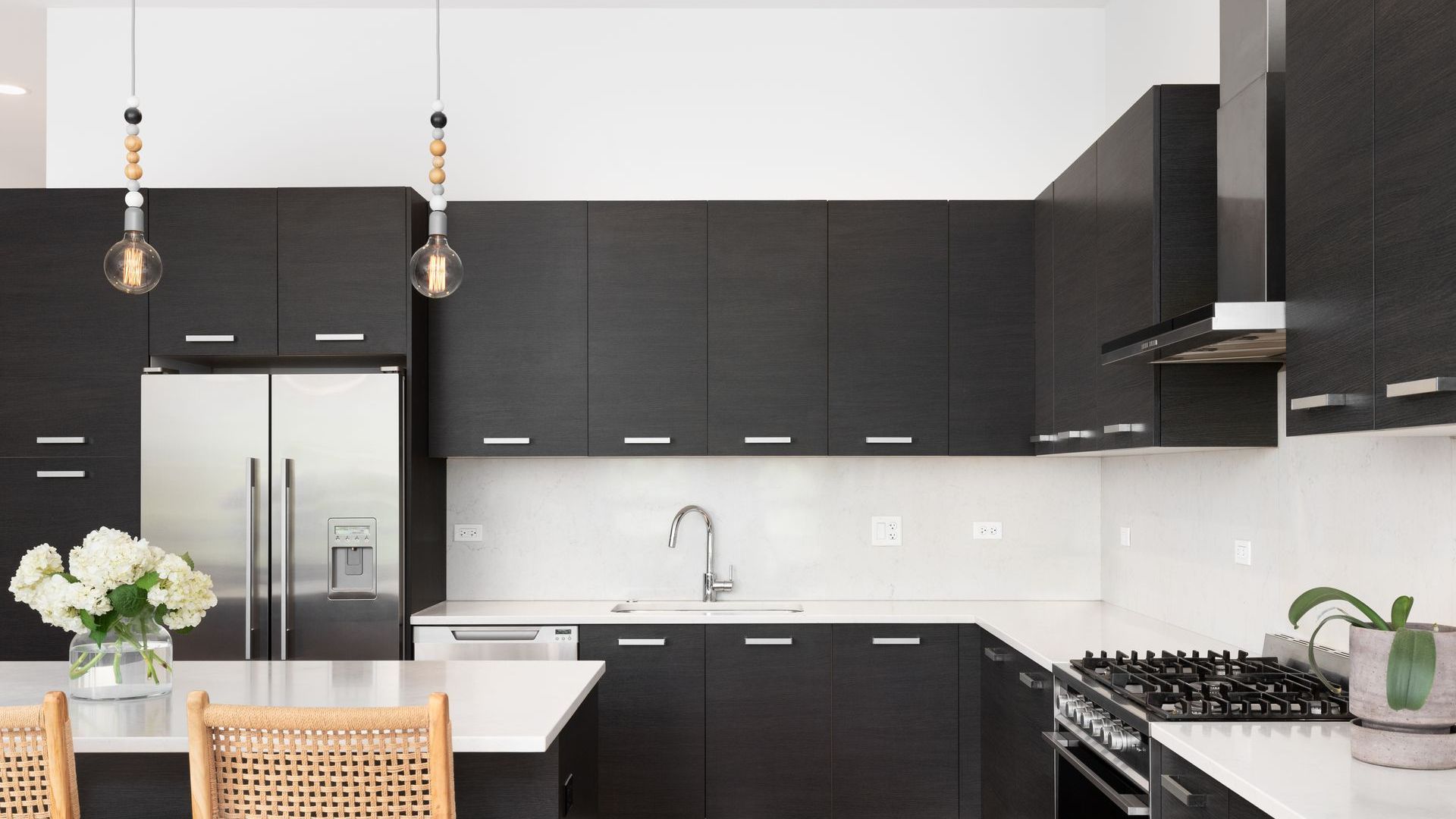 A kitchen with black cabinets and stainless steel appliances