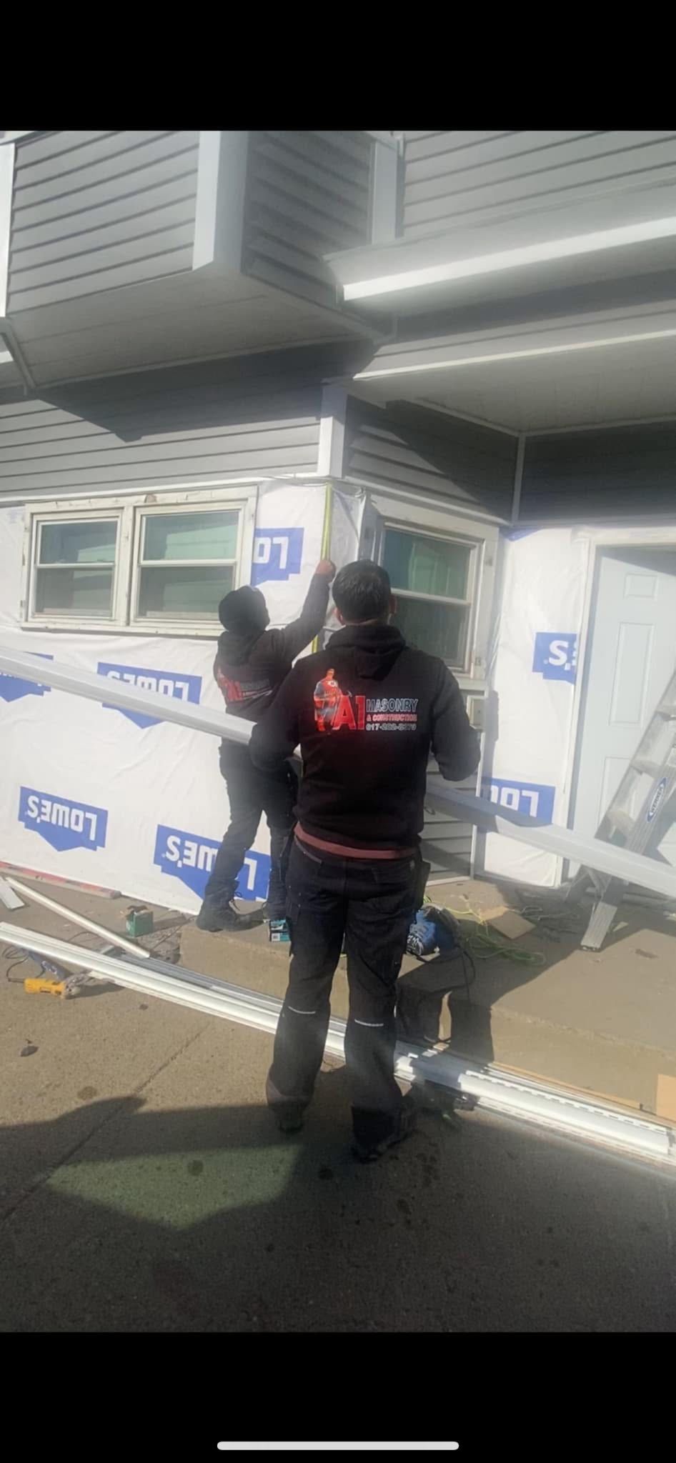 Two construction workers installing trim on a house corner.