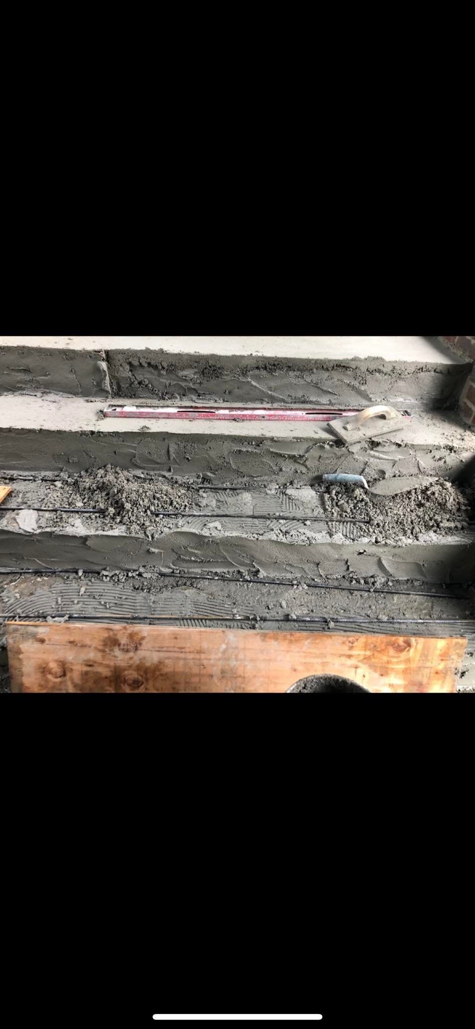 Concrete construction: steps with rebar, gravel, and a level.