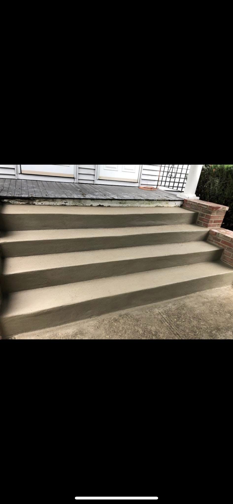 Concrete steps leading up to a porch. Brickwork on the right side.