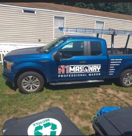 A blue masonry truck is parked in front of a house