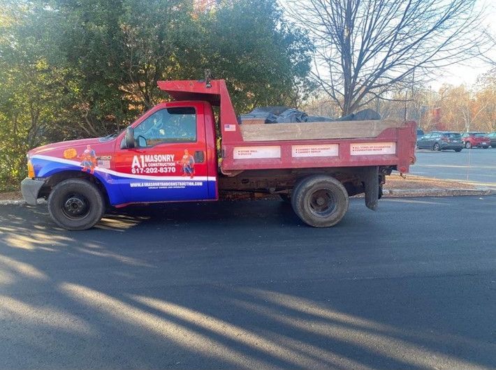 A red and blue dump truck is parked on the side of the road.
