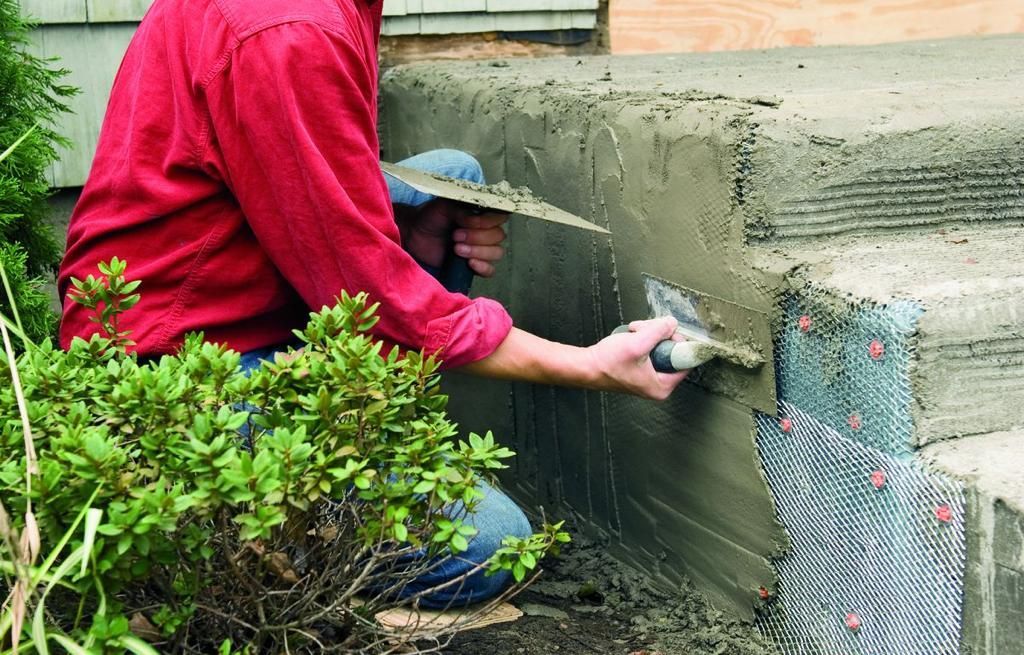 Person applying concrete to steps with a trowel; mesh reinforcement visible.