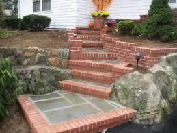 Brick steps leading to a white house, with a brick and rock retaining wall and landscaping.