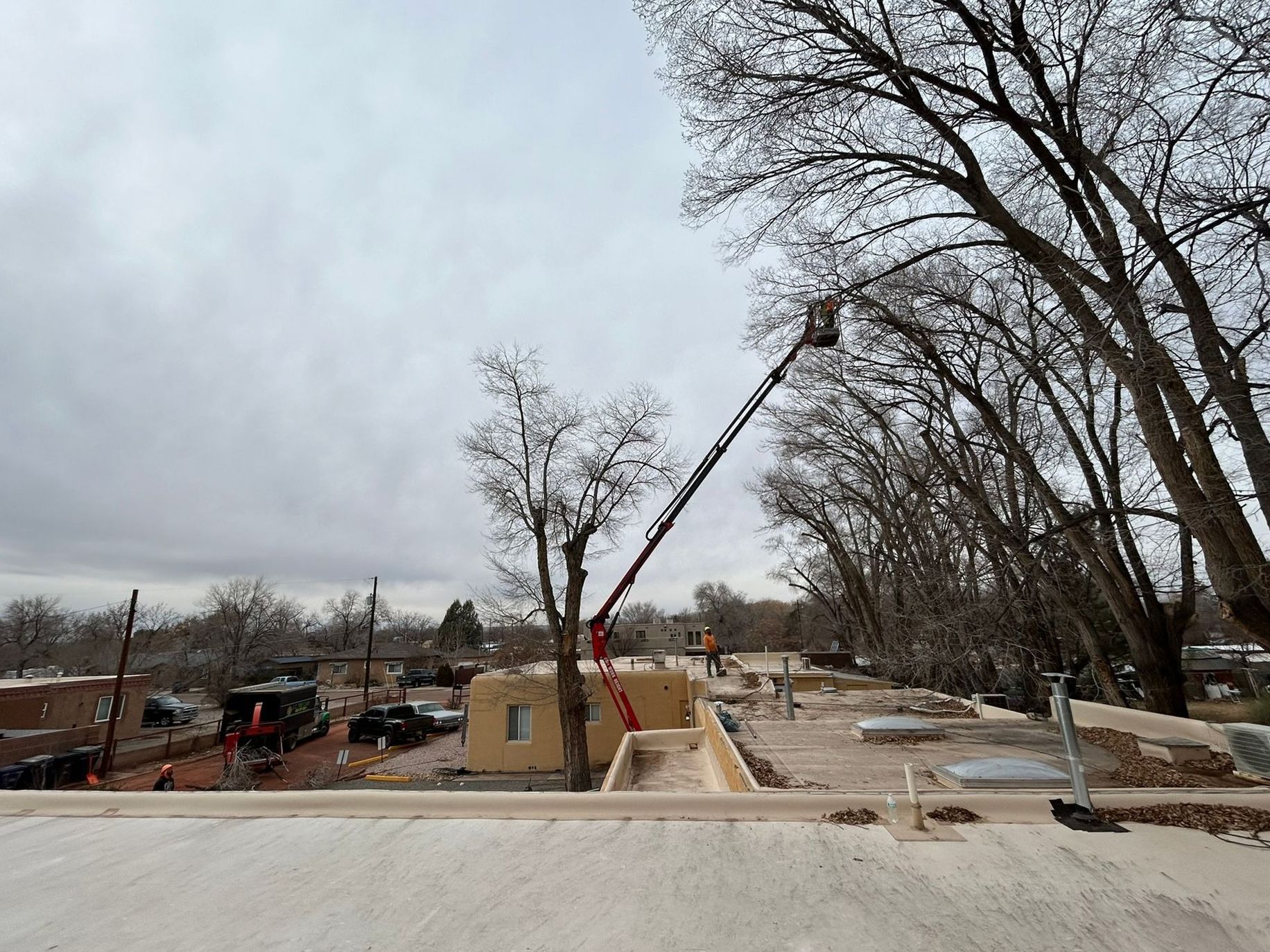 Construction site with crane lifting materials beside a road under cloudy sky