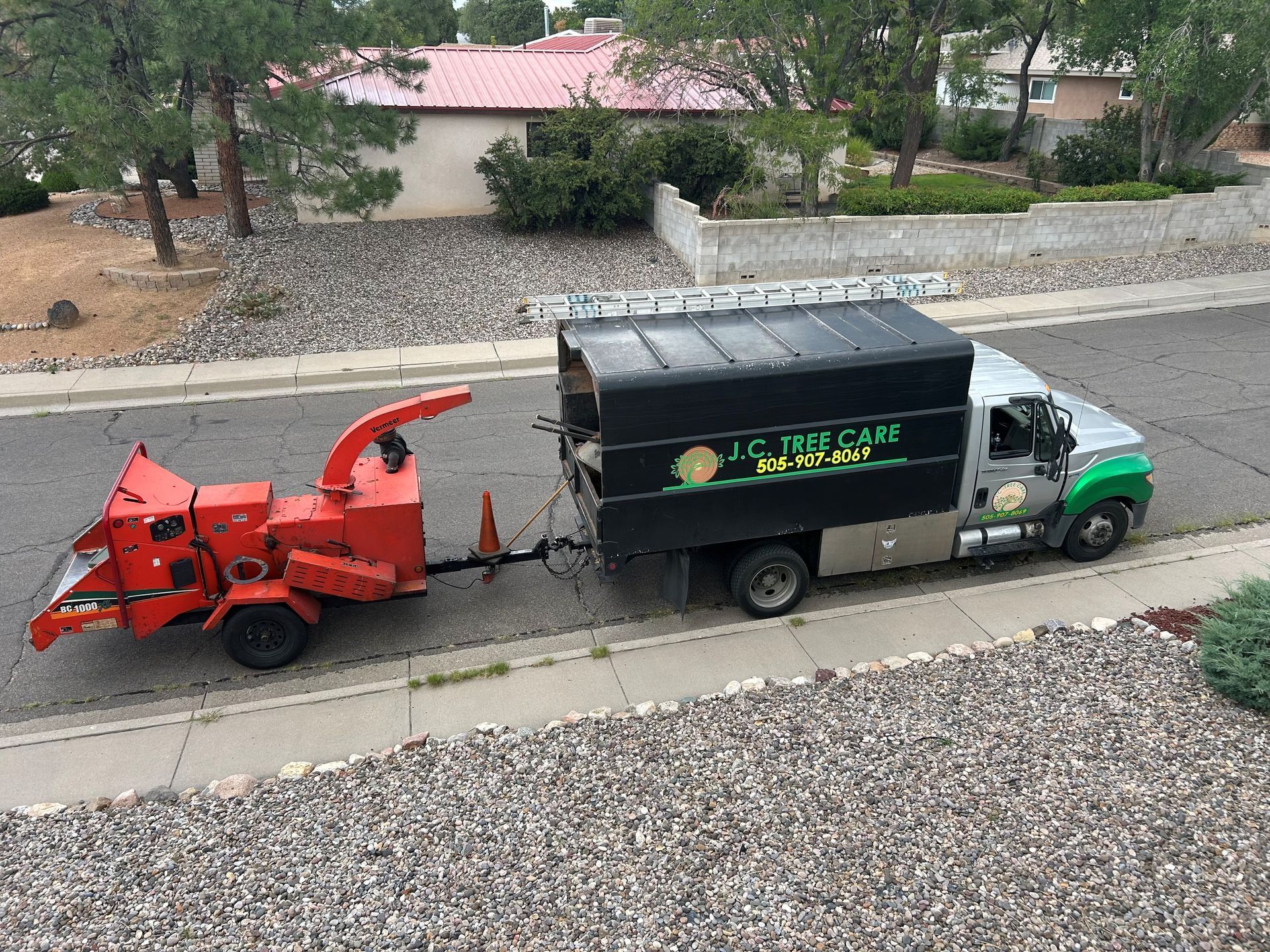 Truck pulling a wood chipper parked on a residential street, likely a tree service vehicle.