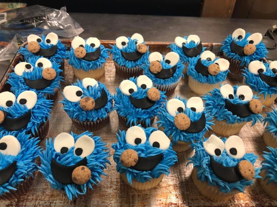 A bunch of cookie monster cupcakes on a tray on a table.
