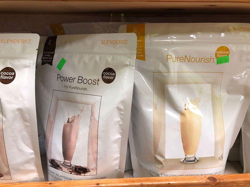 Three bags of protein shakes are sitting on a wooden shelf.