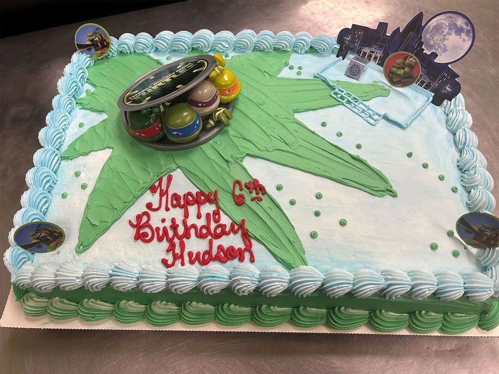 A birthday cake with ninja turtles on it is on a table.