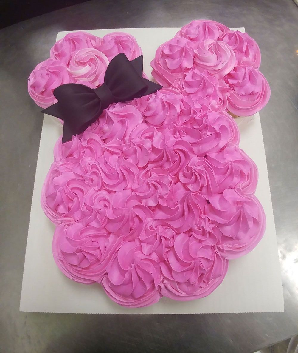A cupcake in the shape of minnie mouse with a black bow