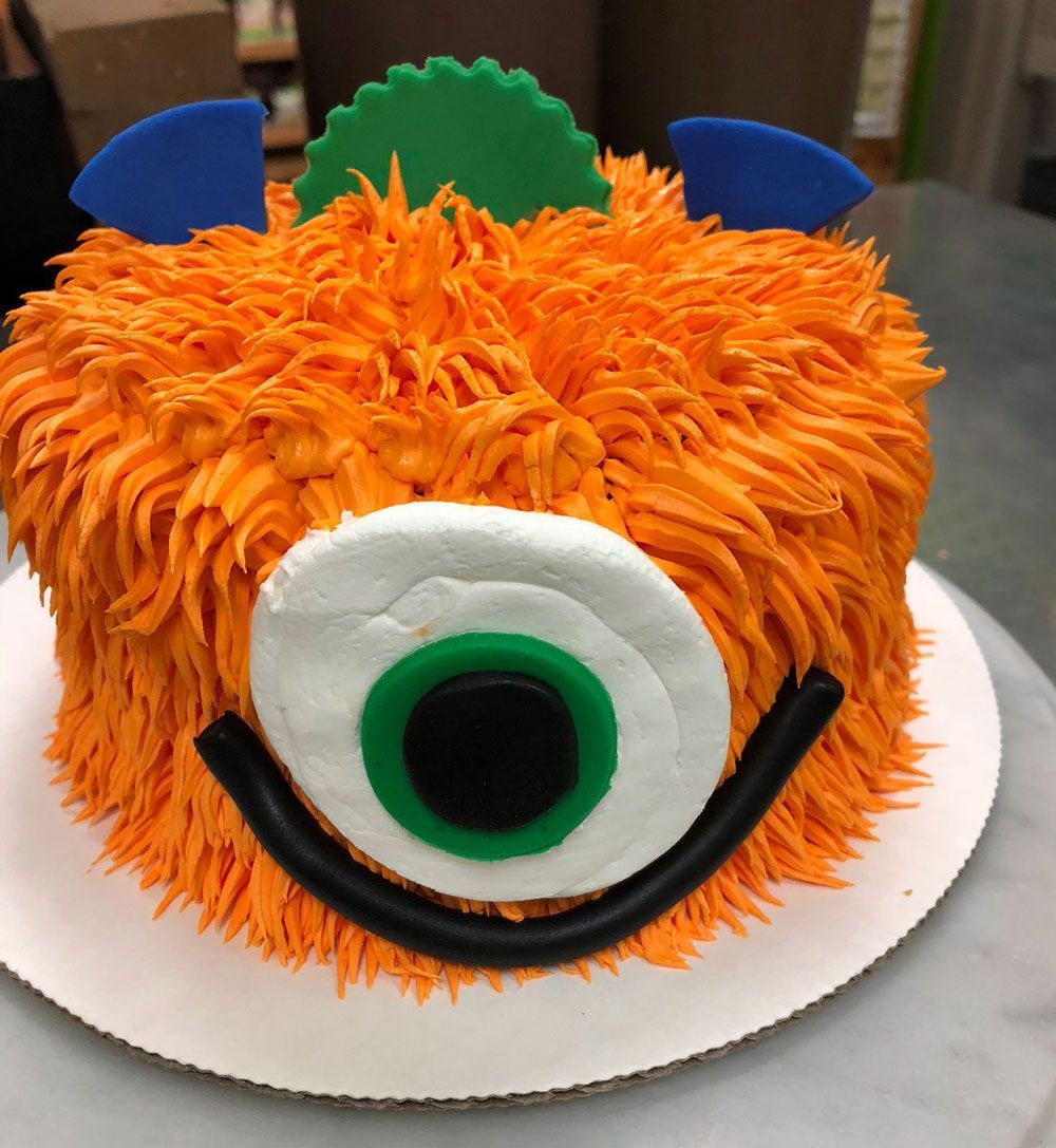 A monster cake with orange frosting and a green eye