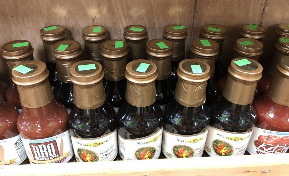 A bunch of bottles of bbq sauce are lined up on a shelf.