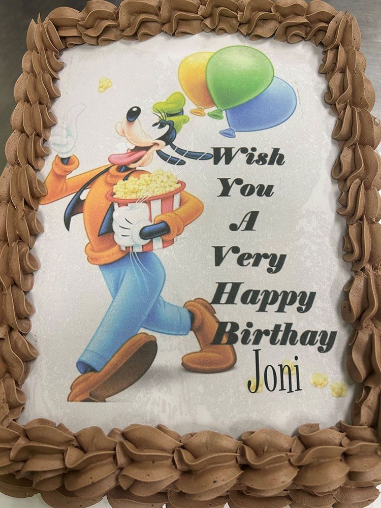 A birthday cake with a picture of goofy holding balloons and popcorn.