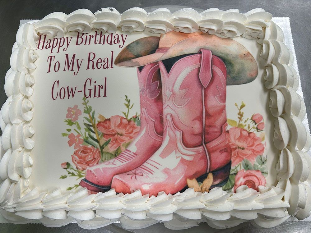 A birthday cake with pink cowboy boots and a cowboy hat on it