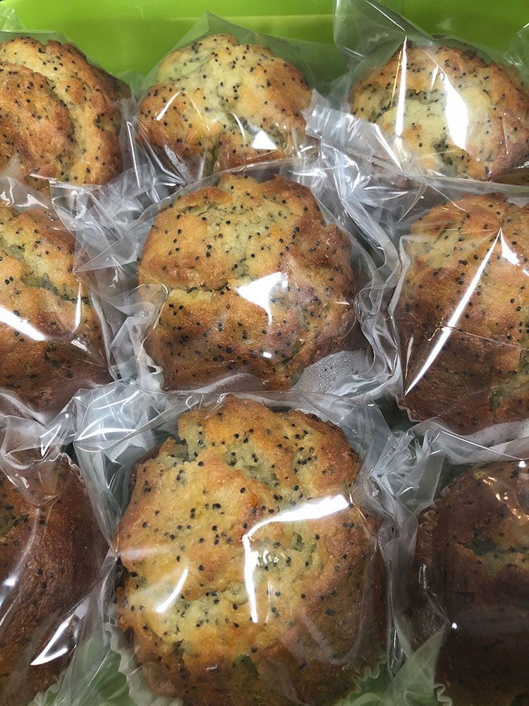 A bunch of muffins wrapped in plastic on a table.