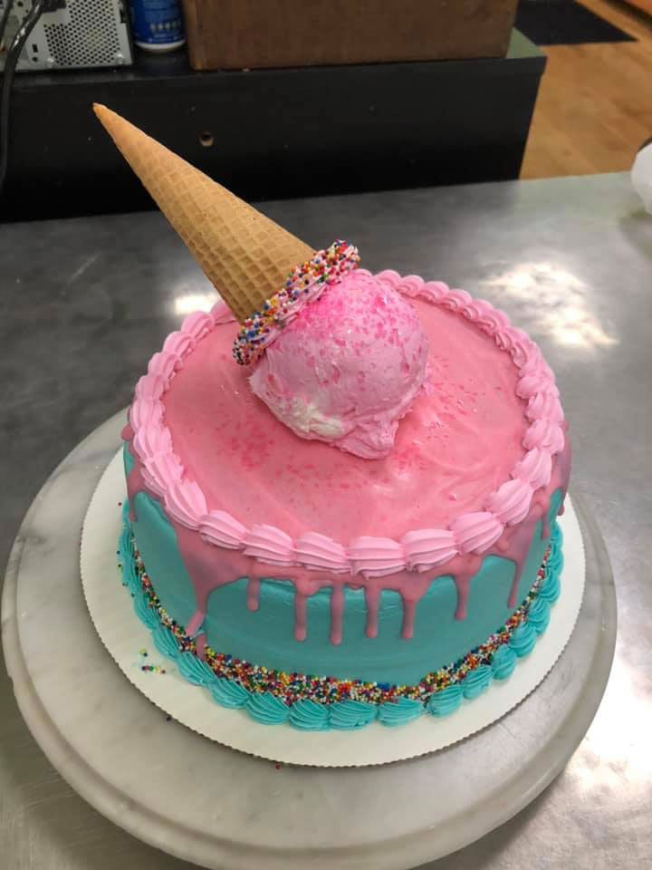 A pink and blue cake with an ice cream cone on top