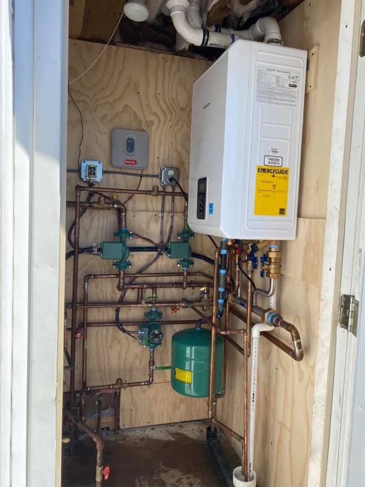 A room with a water heater and a lot of pipes.