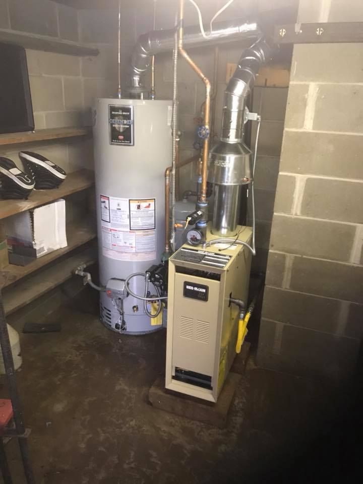 A water heater and a gas boiler are in a basement.