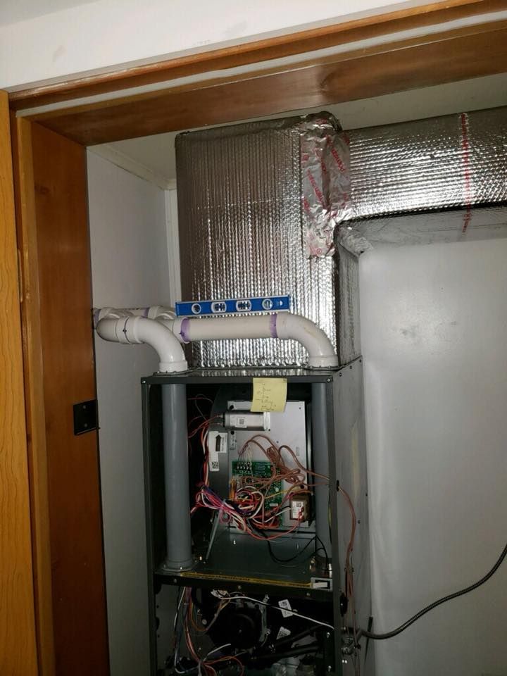 A furnace is sitting in a closet next to a door.