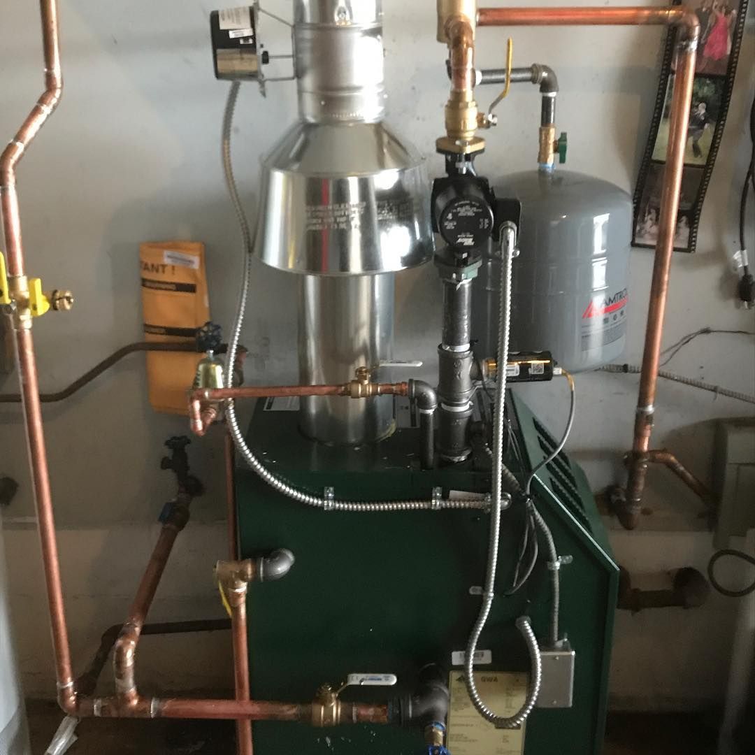 A green boiler with copper pipes connected to it.