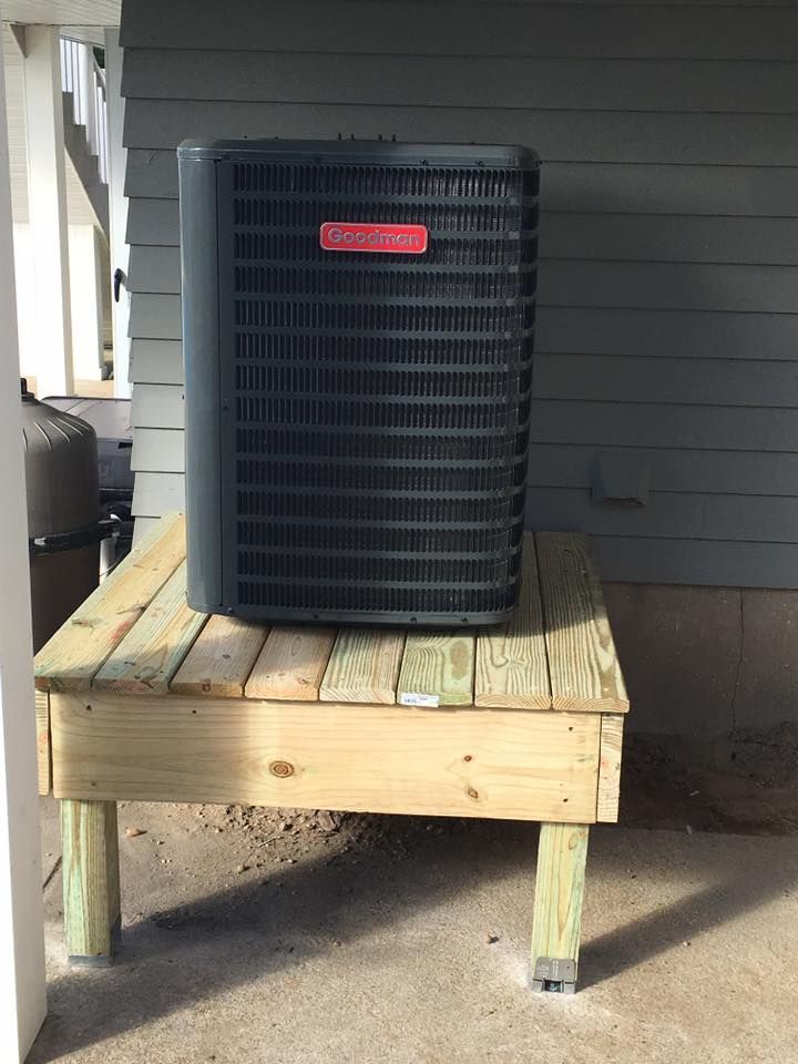 An air conditioner is sitting on top of a wooden platform.