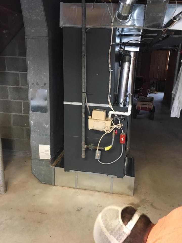 A person is standing next to a heater in a basement.