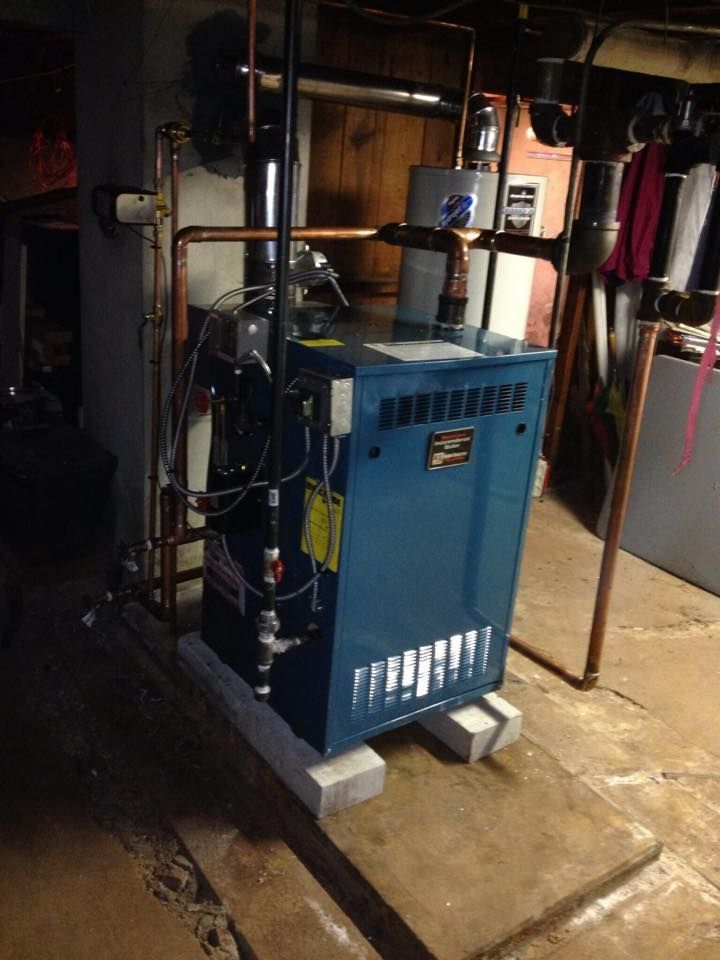 A blue boiler is sitting on a concrete platform in a basement.