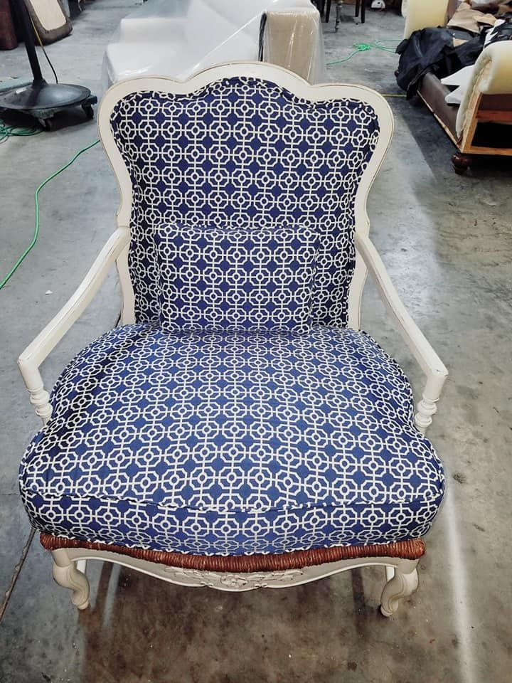 White armchair with blue and white geometric pattern upholstery, dark wood trim.