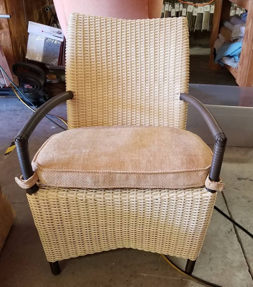 Wicker chair with brown cushion and armrests. Beige woven body. Brown, curved armrests.