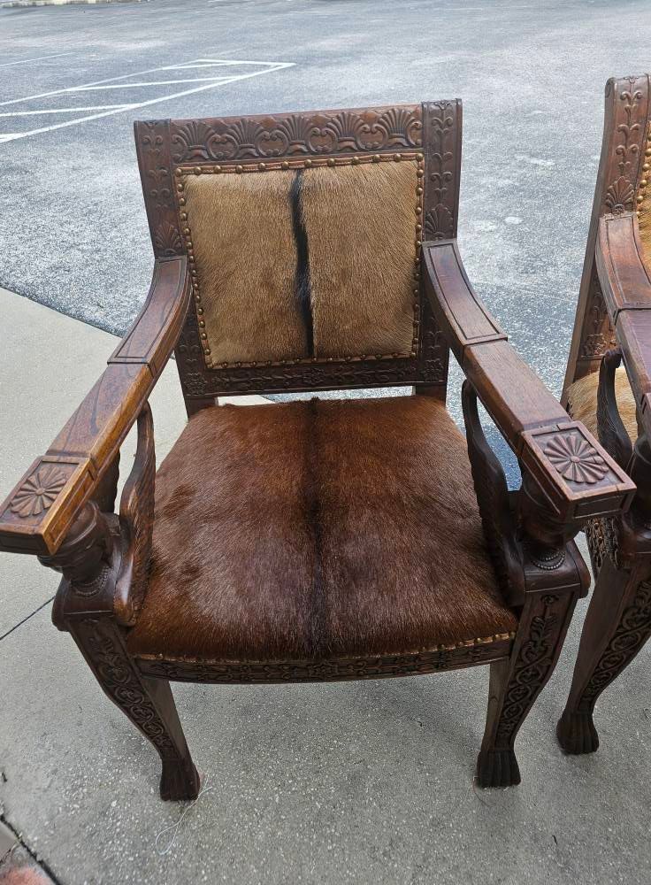 Wooden chair with carved details, hide seat and back, outdoors.