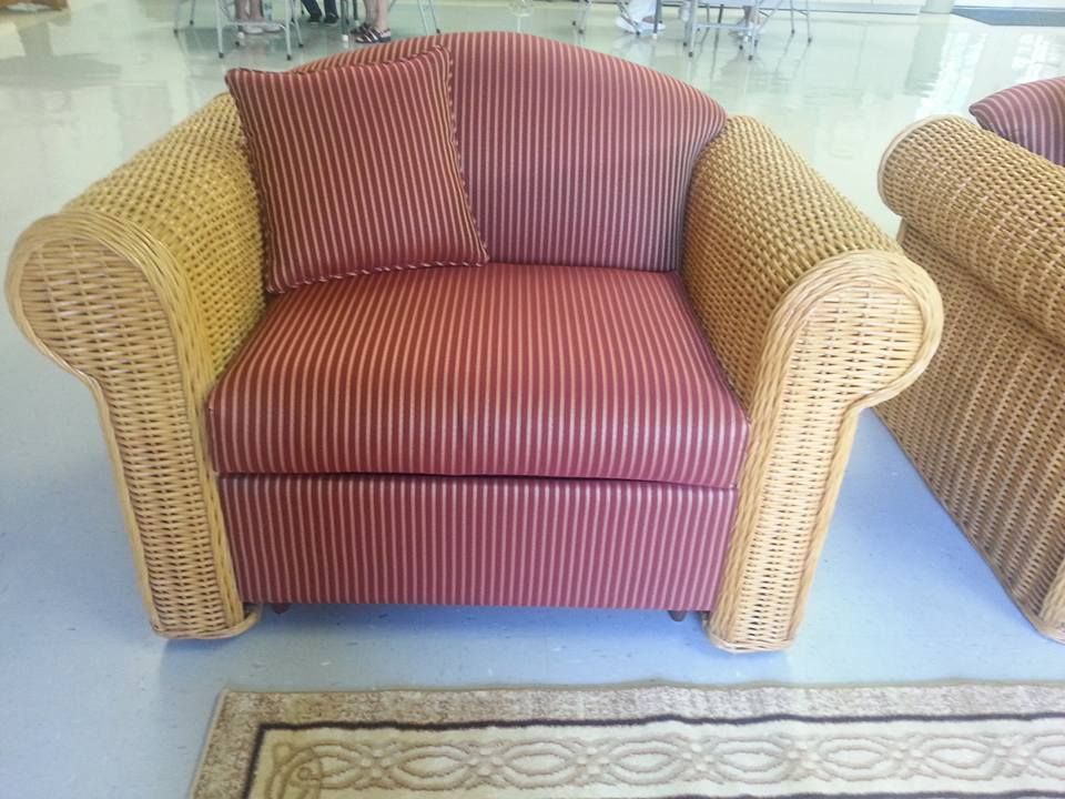 Wicker armchair with red pinstripe cushions and a matching pillow; light brown armrests.
