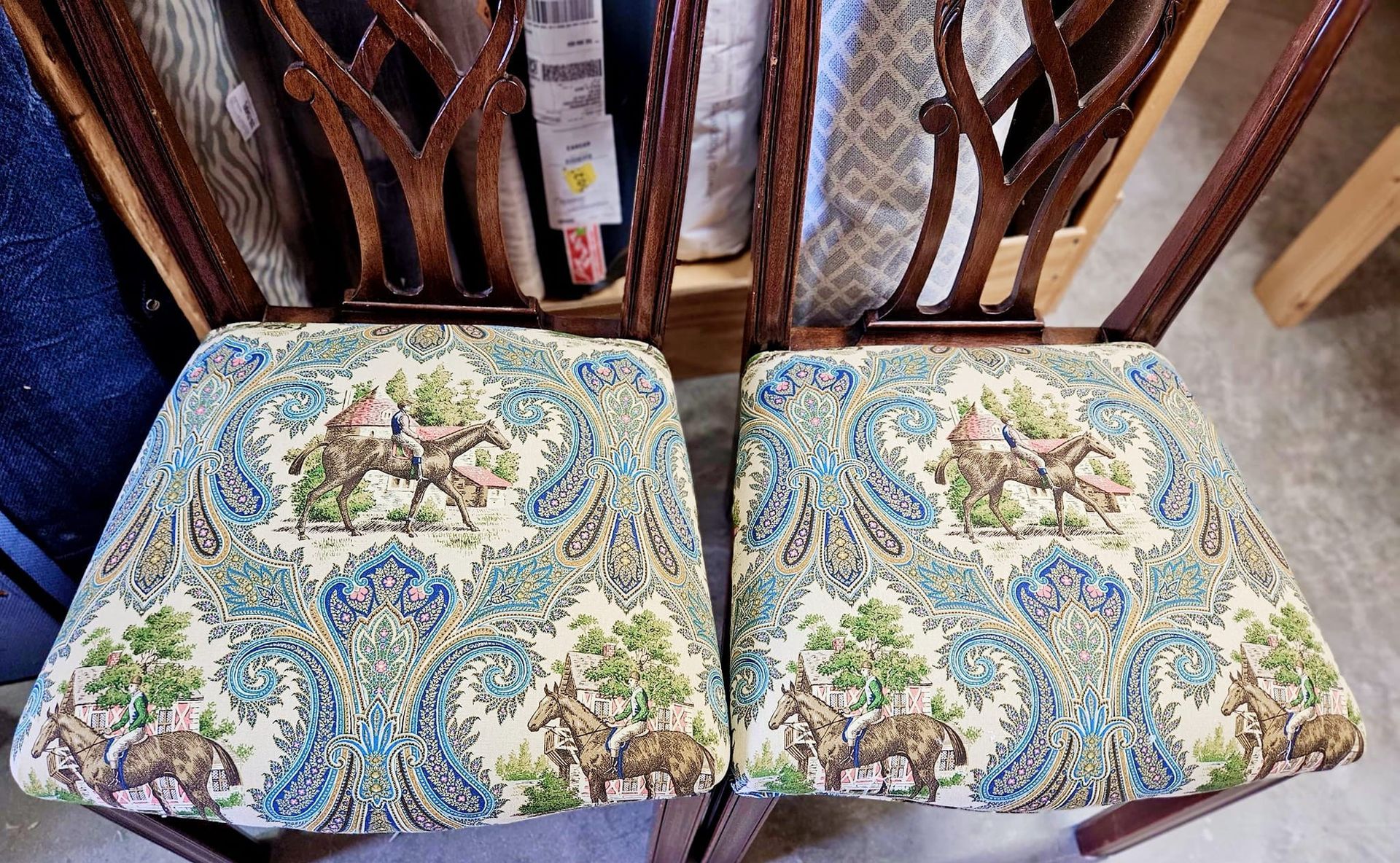 Two antique chairs with blue patterned seats and carved wooden backs.