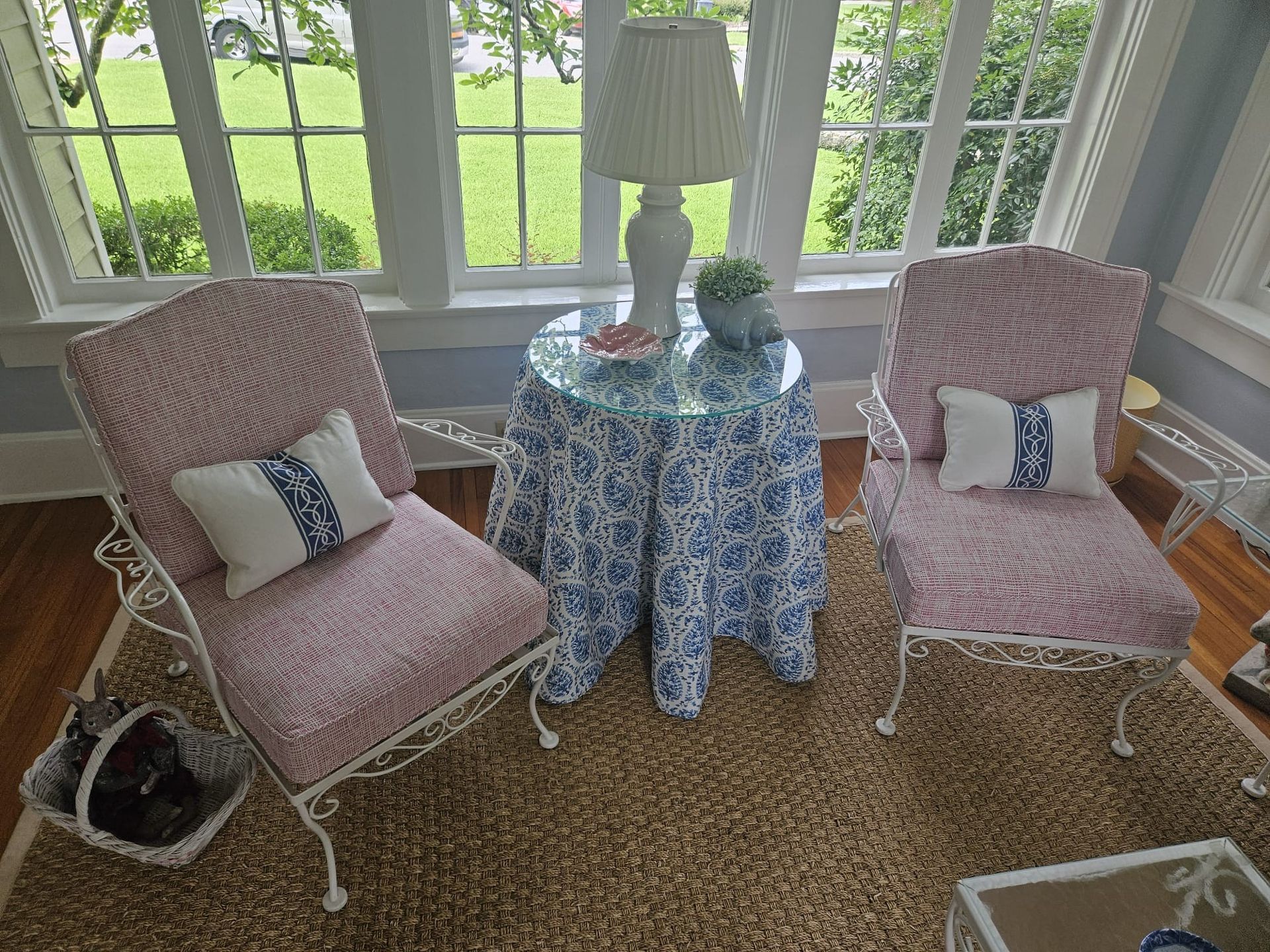 Two floral armchairs flank a round table set in a sunroom.