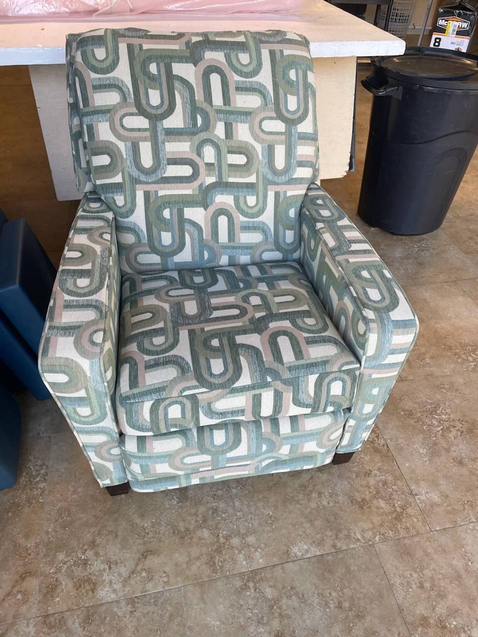 Upholstered armchair with blue and white geometric pattern; tan tile floor.