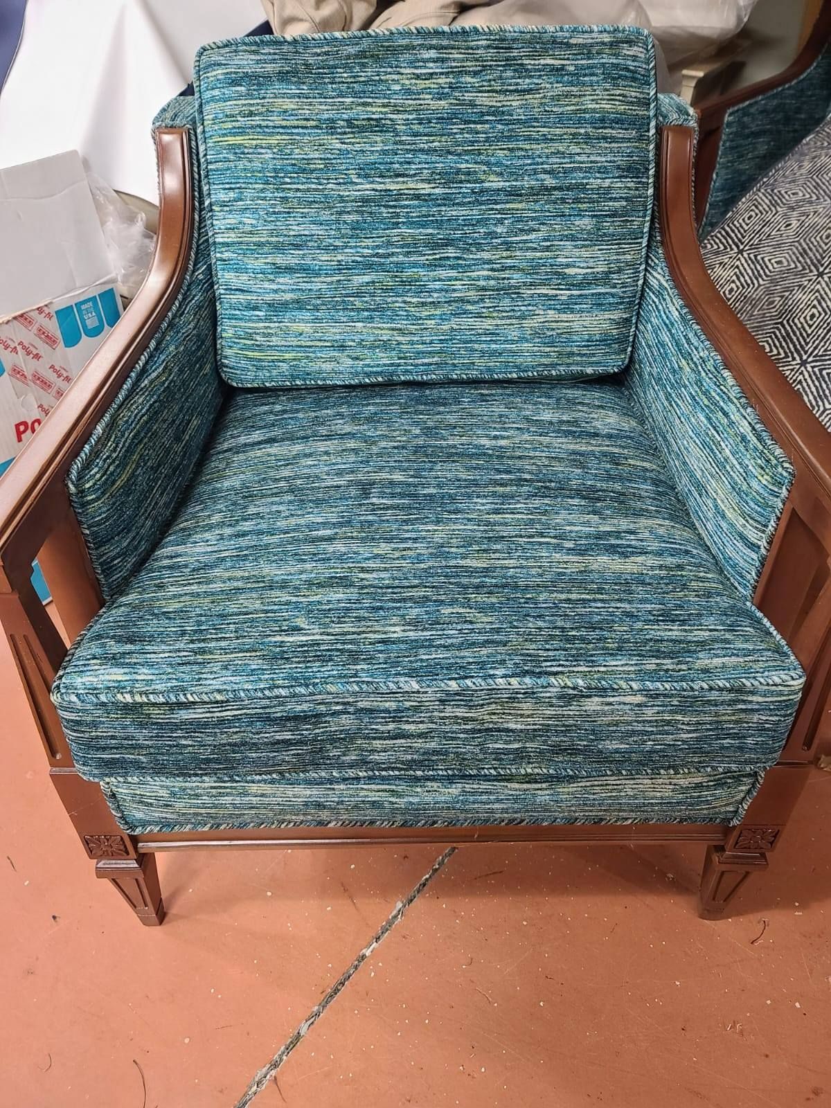 Armchair with teal and white patterned fabric, brown wooden frame.