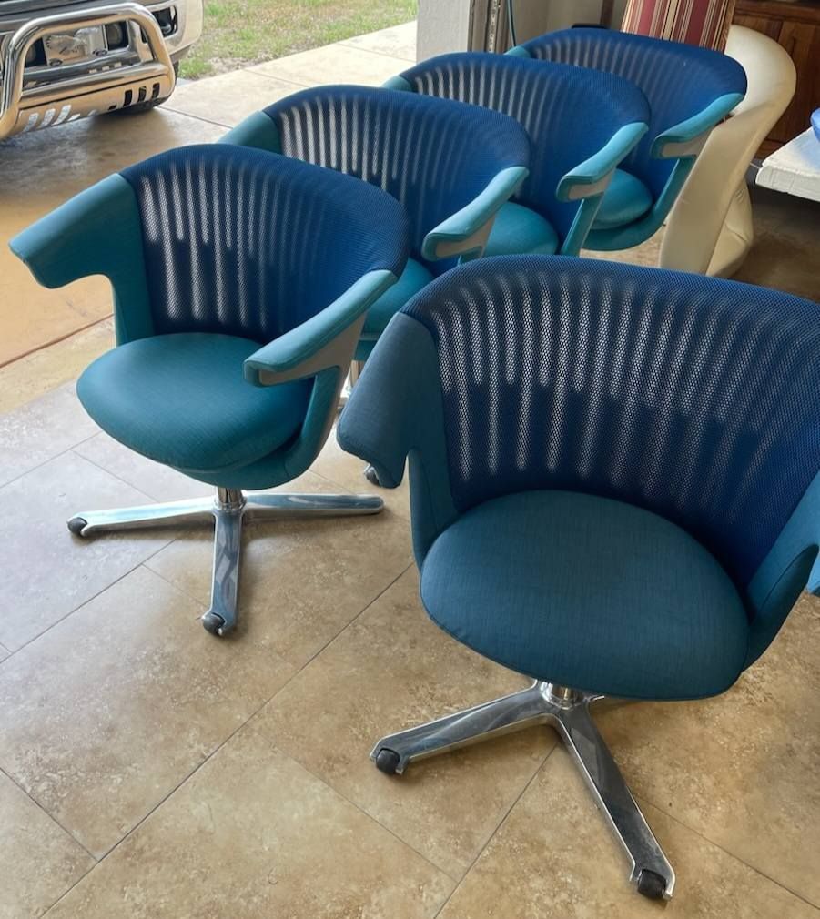 Five blue office chairs with chrome bases, in a garage.
