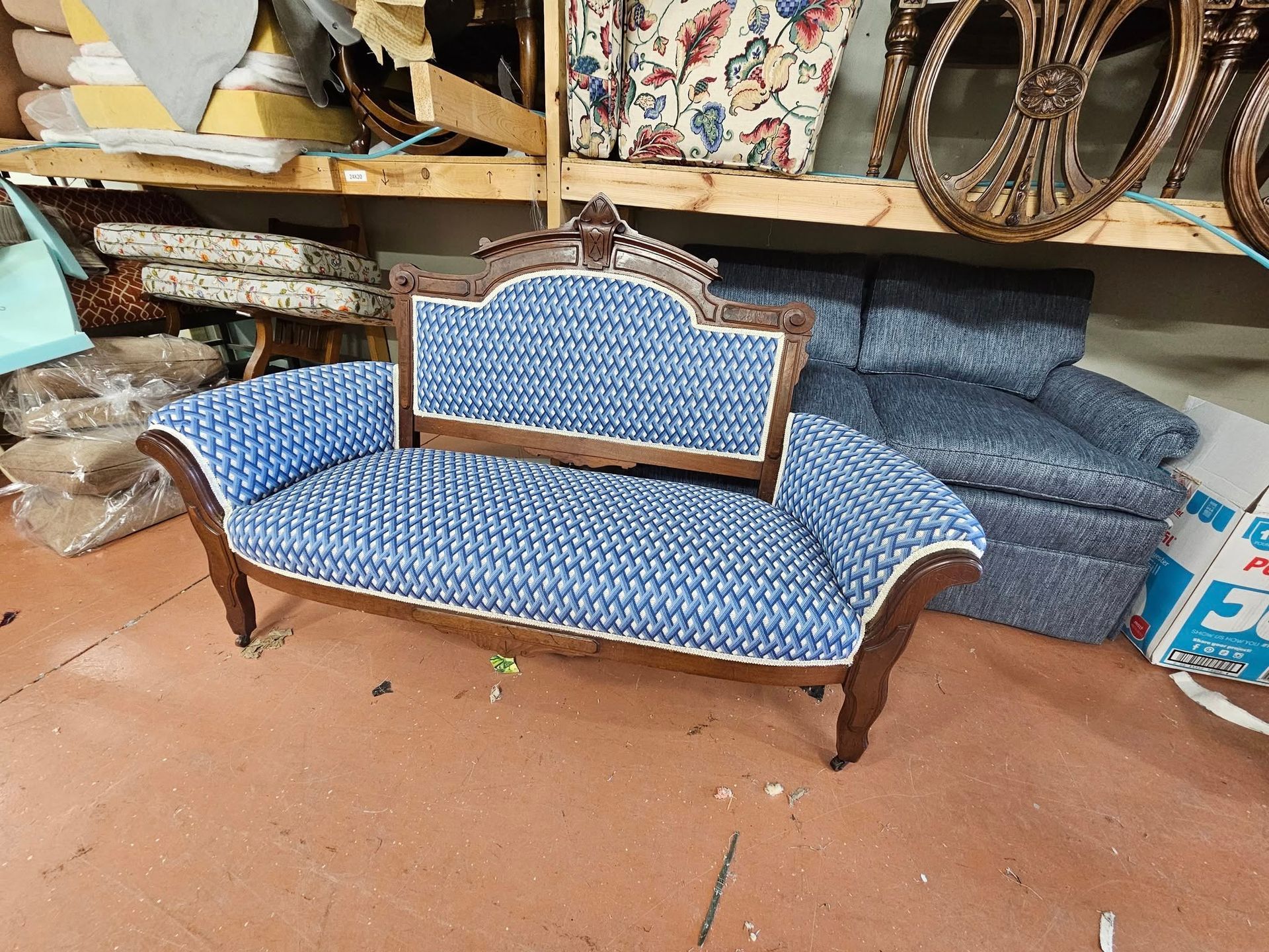 Small blue upholstered settee in a workshop, brown wood frame and white trim.
