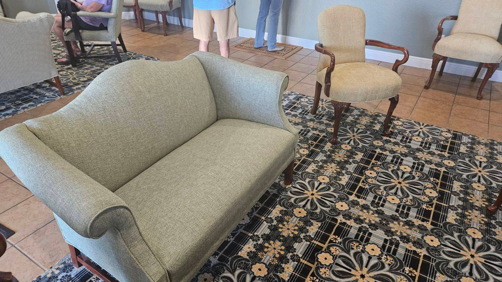 A light green sofa and beige chairs on a patterned rug in a well-lit room.