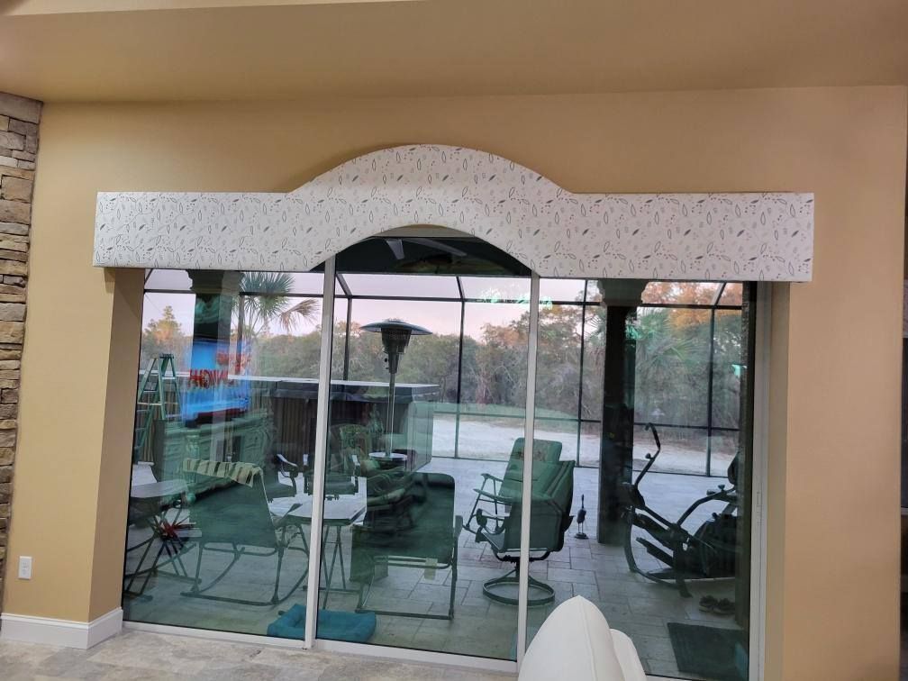 Arched white trim above glass sliding doors, looking out to a pool and patio. Beige walls.