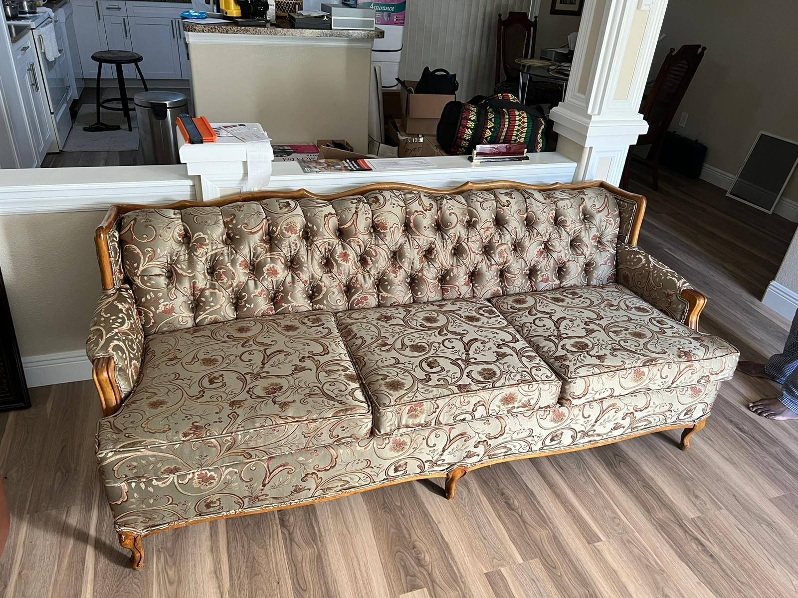 Vintage floral-patterned sofa with wooden frame, in a living room setting.