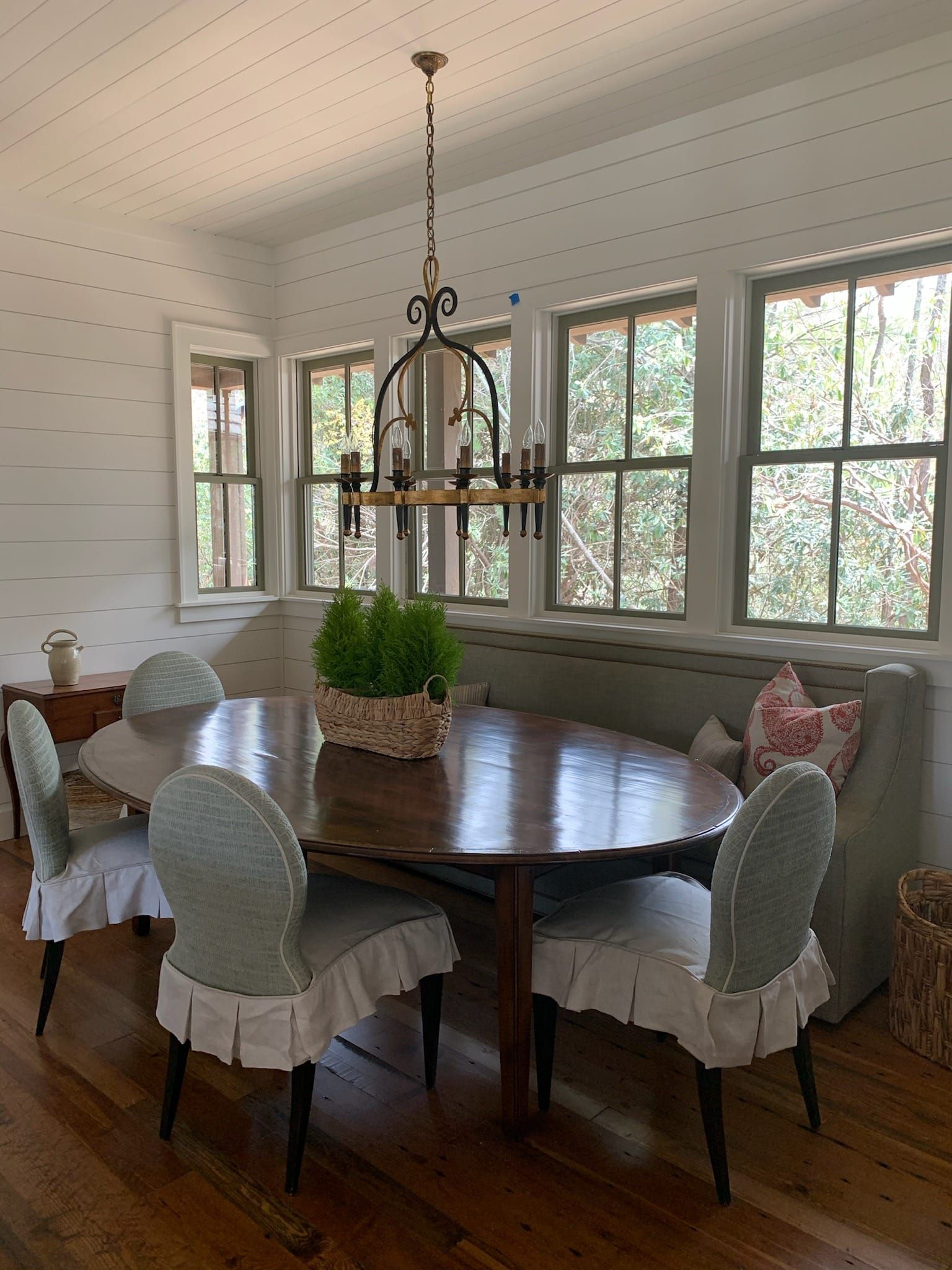 Dining room with a dark wood table, chairs with ruffled skirts, and a decorative chandelier.