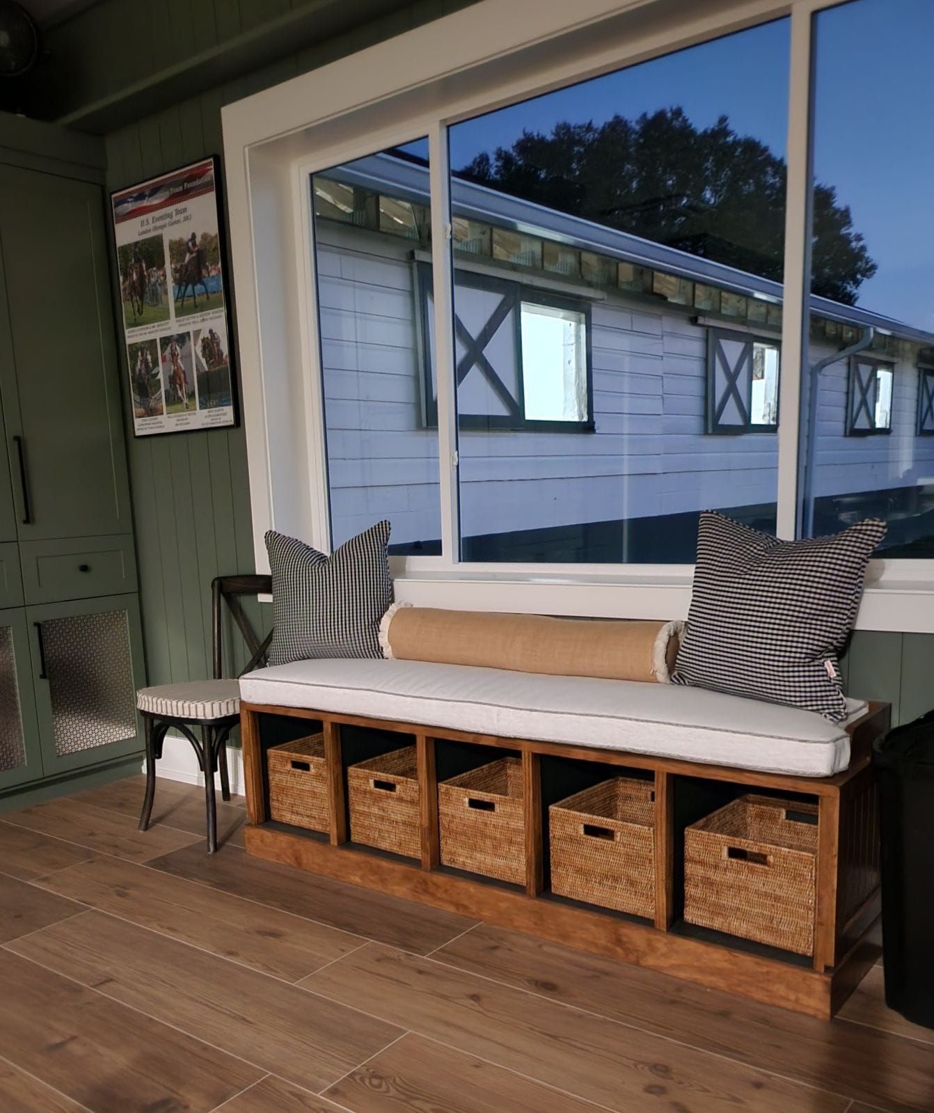 Cozy seating area with bench and storage baskets, overlooking a horse stable.