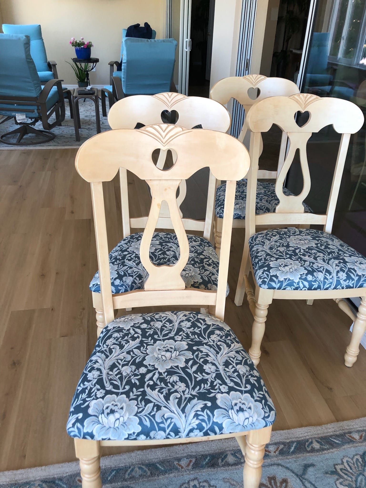 Four light wooden chairs with blue patterned seats, arranged indoors.