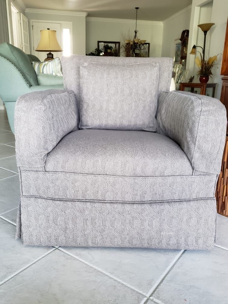Gray upholstered armchair with matching pillow in a bright room.