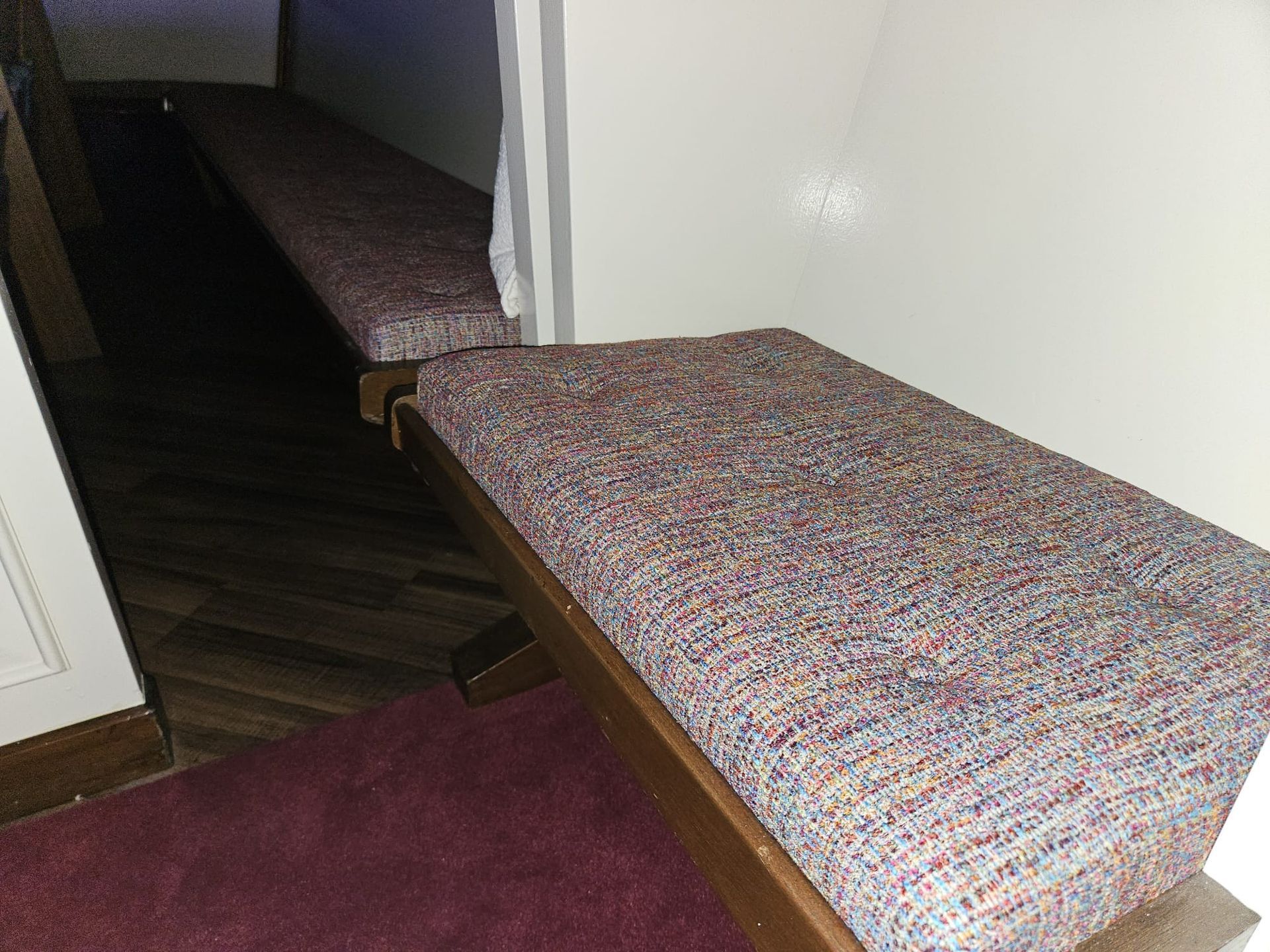 Two padded benches with colorful fabric in a hallway.
