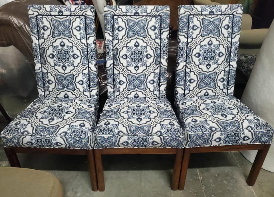 Three upholstered dining chairs with blue and white patterned fabric.