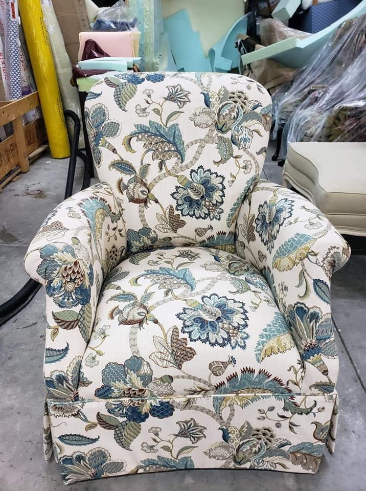 Upholstered floral armchair in off-white, blue, and brown, indoors.