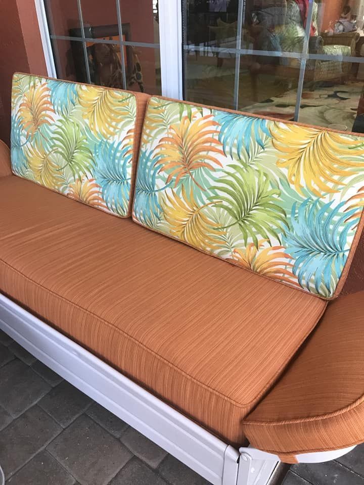 Outdoor sofa with orange cushions and tropical print back cushions.