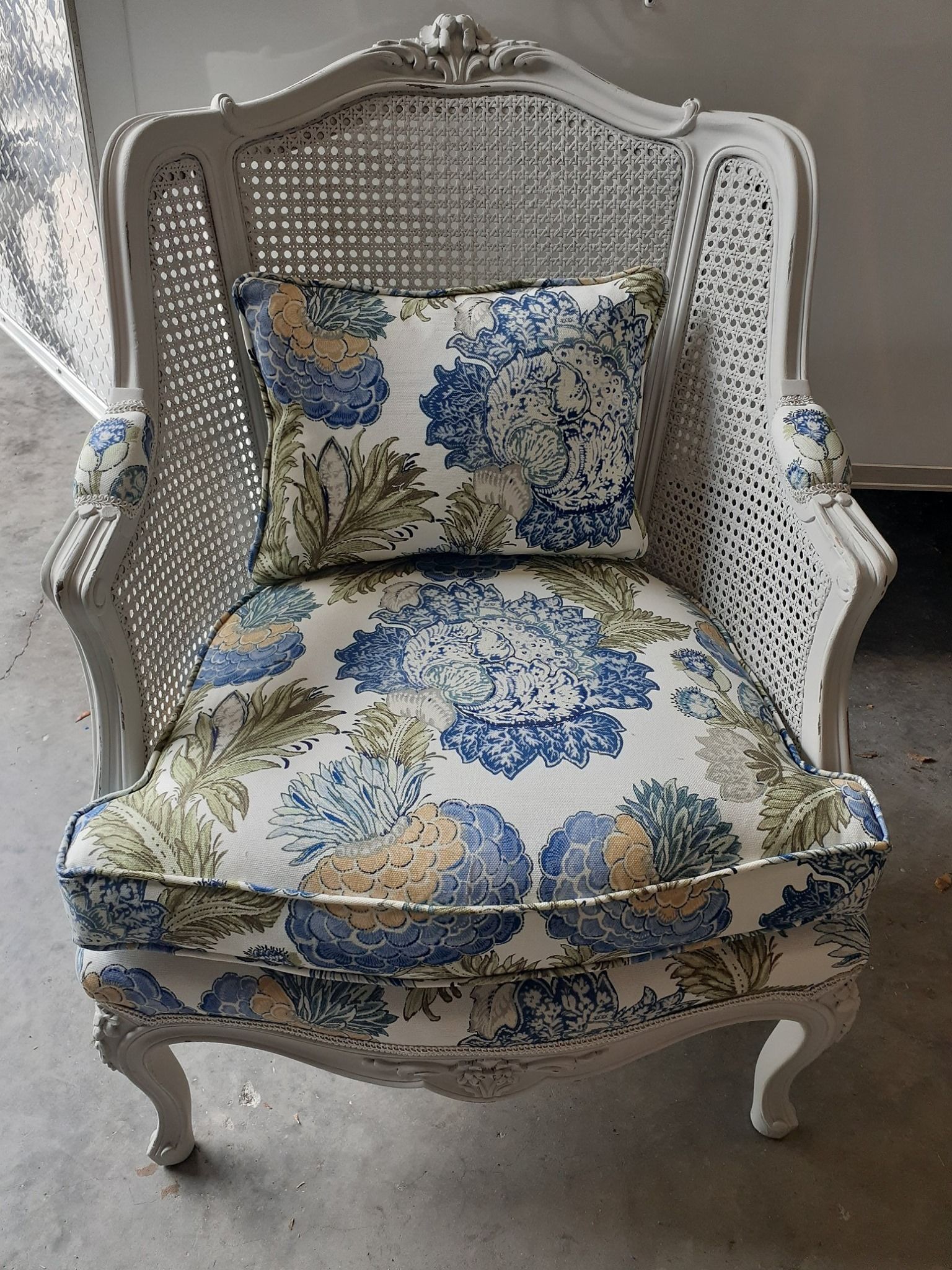 White wicker chair with blue and yellow floral cushions.