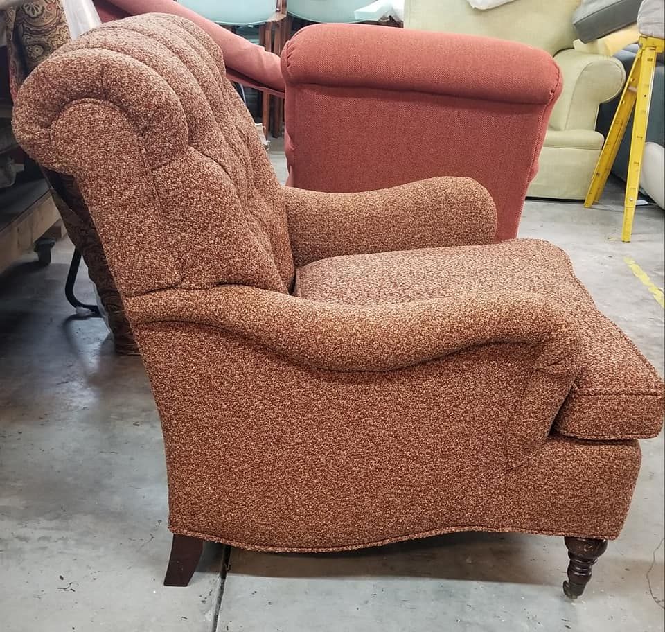 Brown upholstered armchair with rolled arms and carved legs.